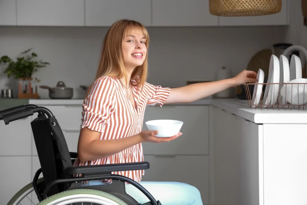 Girl in wheelchair doing the dishes in her kitchen