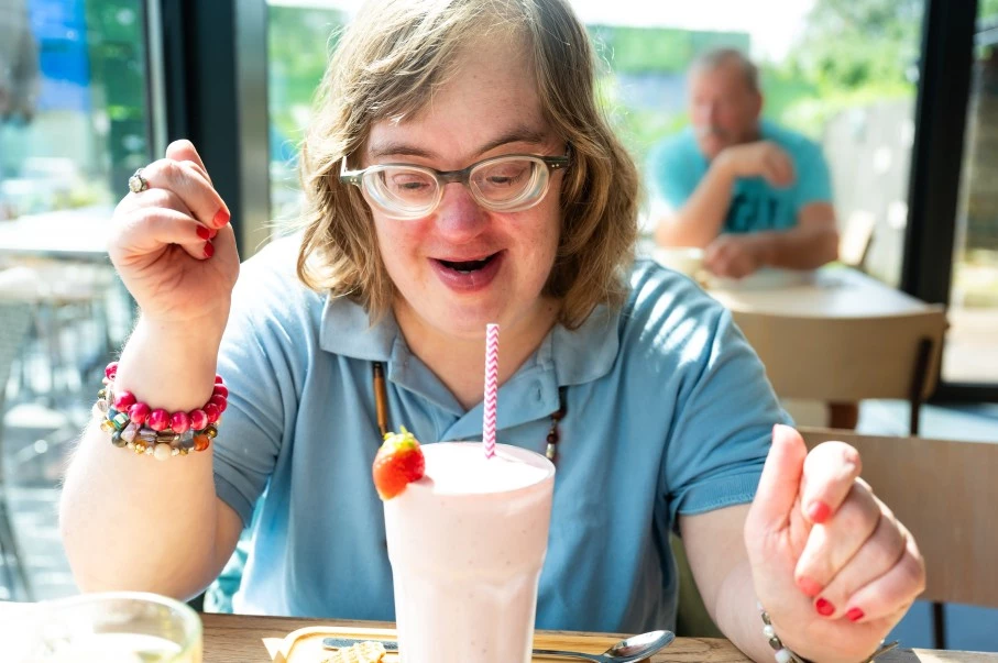 Girl with down syndrome sitting at cafe with a strawberry smoothie