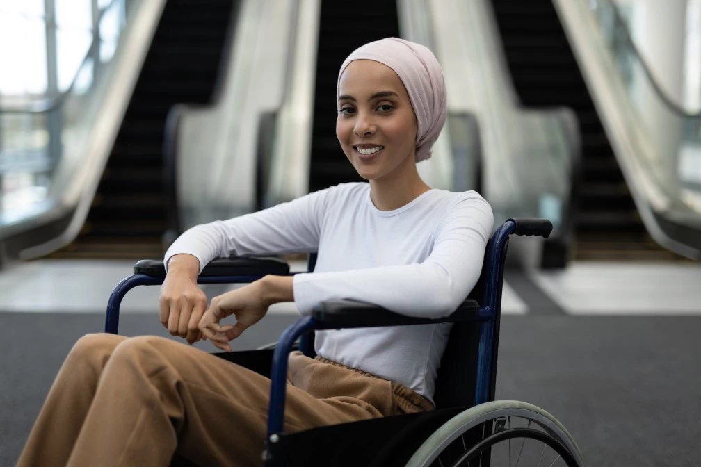 Woman with head scarf in wheelchair smiling at camera
