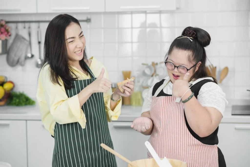 Girl with down syndrome in kitchen smiling with support worker
