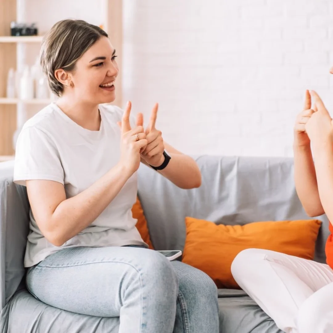 Two women sitting on couch communicating via sign language
